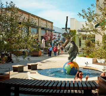 Corte Madera town center people shopping and congregating around playful fountain of an elephant dancing on a globe.